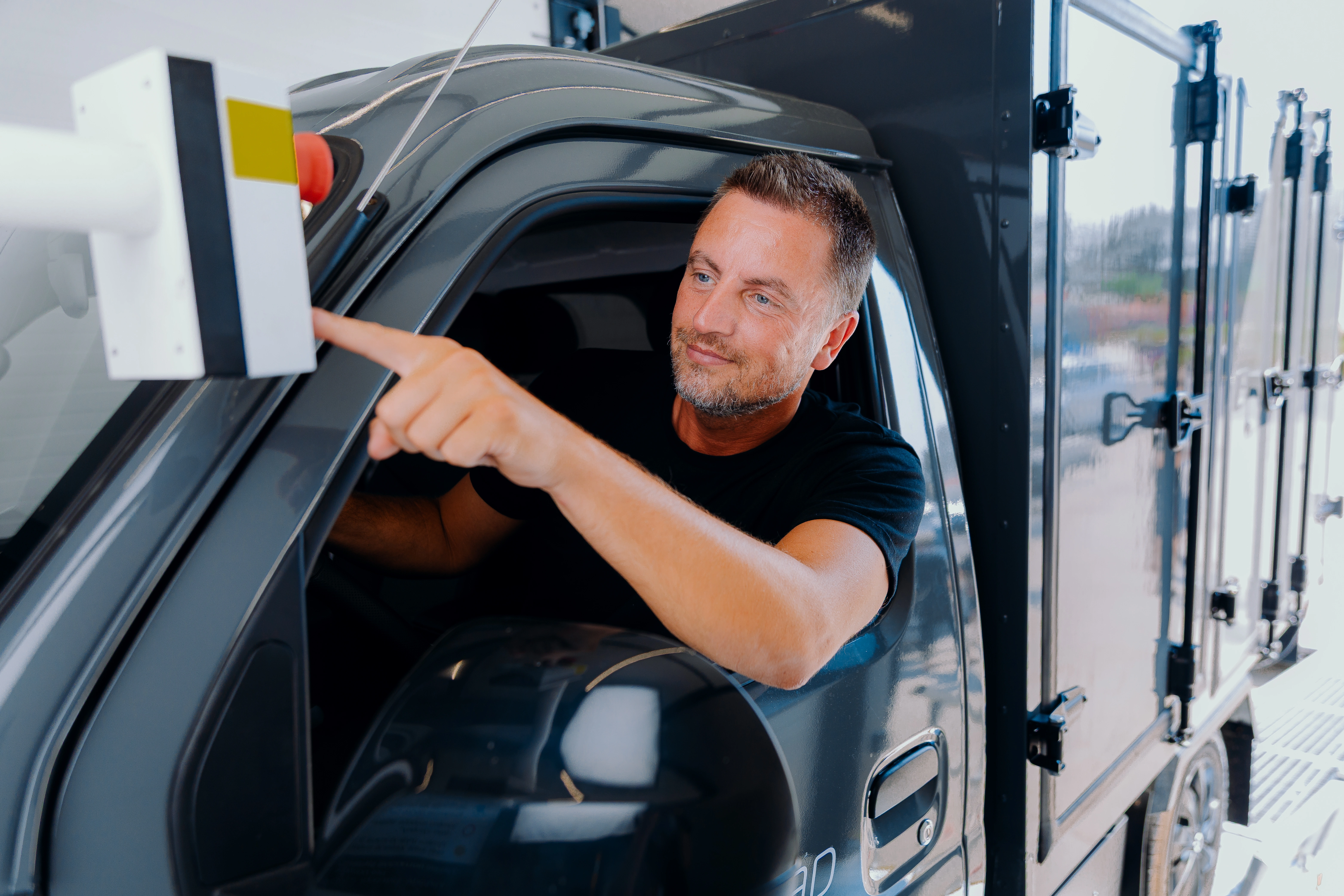 A driver reaching out of the van window to press the swap station's start button